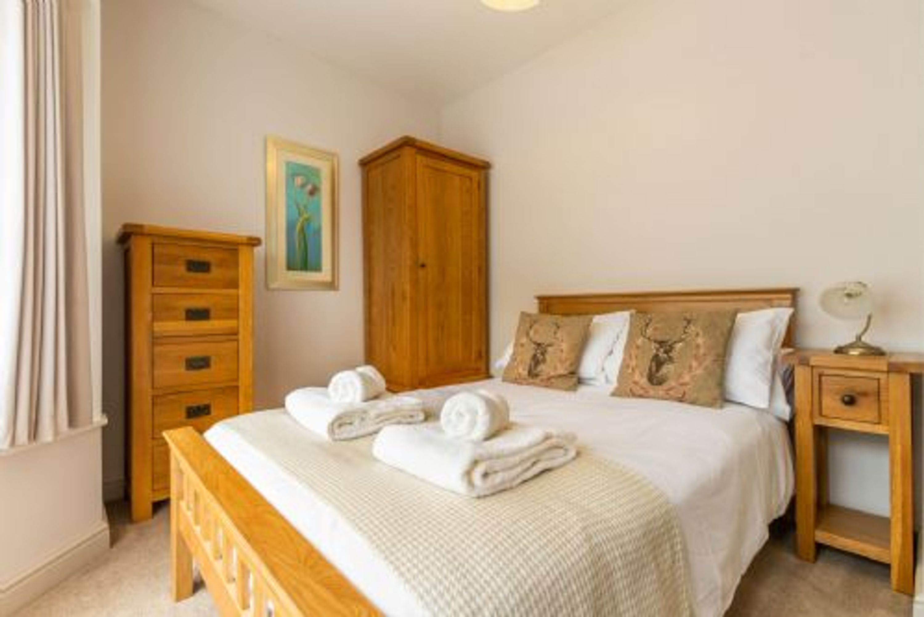 A bedroom with a bed, wooden dresser, and a nightstand.