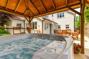 A hot tub under a wooden pergola with a house in the background. - Host Stay Woodside House (Norwich)