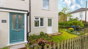 A two-story house with a teal front door, a small front yard, and a wooden fence. - Host Stay Corner Cottage (Norwich)
