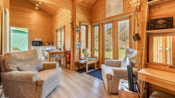 A cozy cabin interior with wooden walls, a dining area, and a seating area with a television.