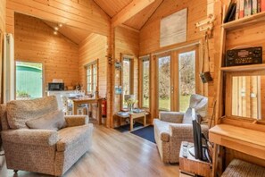 L’intérieur chaleureux d’un chalet avec des murs en bois, un coin repas et un espace salon équipé d’un téléviseur.