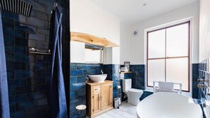 A modern bathroom with a freestanding bathtub, a wooden vanity, a large window, and a shower area. - Host Stay Villa Otto (Cromer)