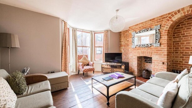 A living room with a brick fireplace, a television, and a sofa. - Host Stay Villa Otto (Cromer)