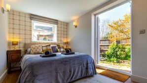 A bedroom with a large bed, a window with a view of the outdoors, and a wooden floor. - Host Stay St Joseph s Cottage (Sheringham)