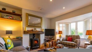 A cozy living room with a fireplace, television, and comfortable seating. - Host Stay St Joseph s Cottage (Sheringham)