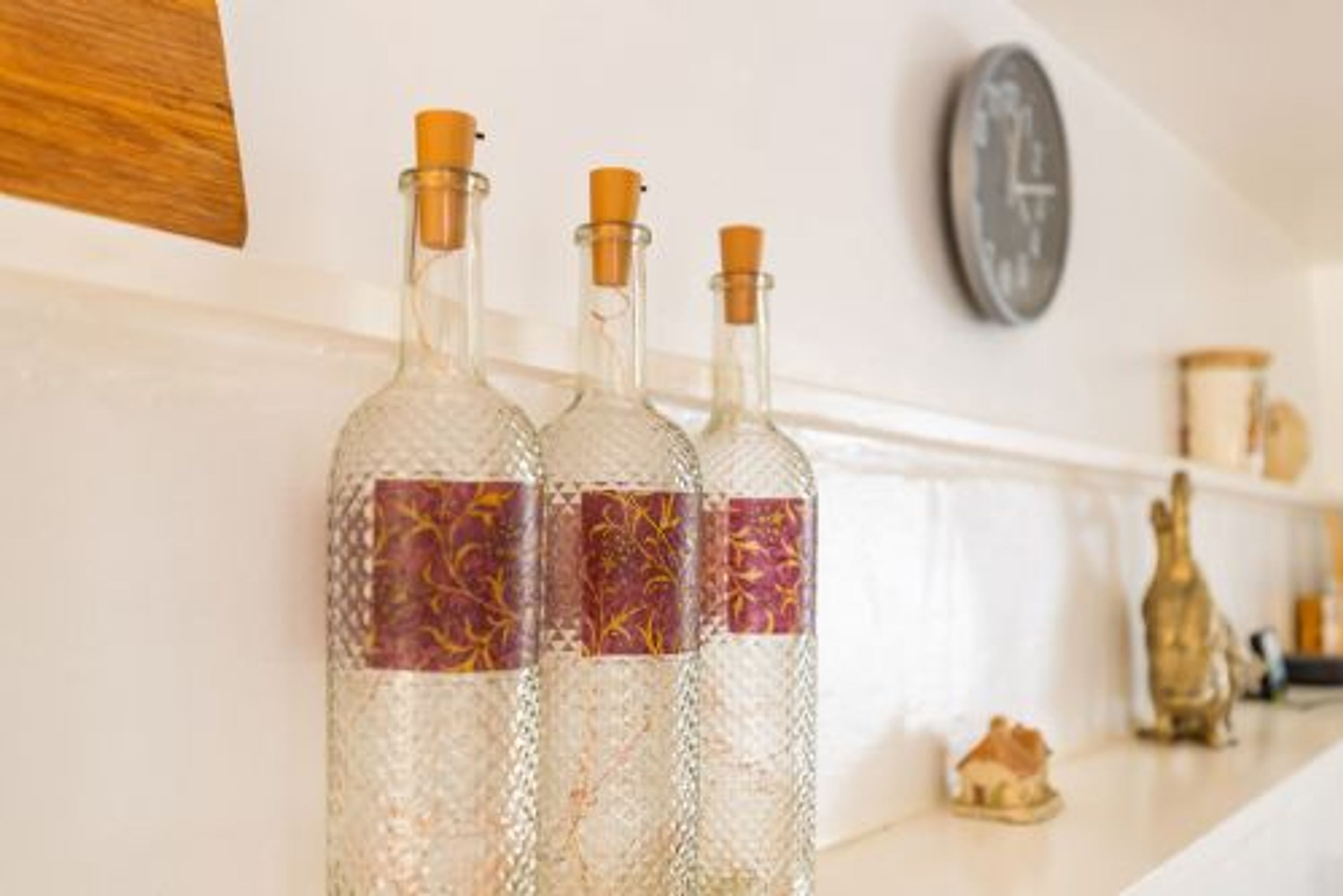 Three glass bottles with cork stoppers on a white shelf.