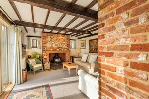 A cozy living room with exposed wooden beams, a brick fireplace, and comfortable seating. - Host Stay Woodfalls Barn (Norwich)