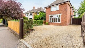 Une maison d’habitation avec une allée en gravier, une clôture en bois et un jardin.