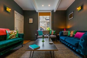 A modern living room with two sofas, a coffee table, and a window with a view. - Host Stay Princes Cottage (Norwich)