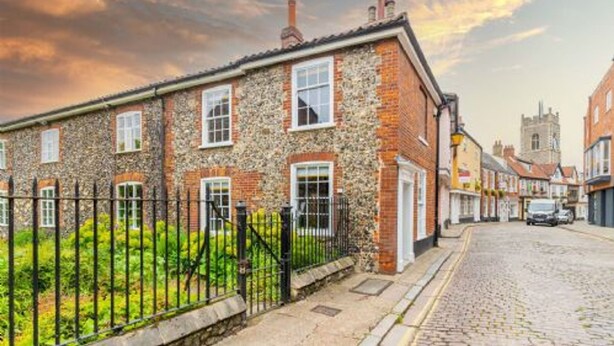 Un bâtiment traditionnel en pierre, doté d’une façade en briques, de nombreuses fenêtres et situé sur une rue pavée.