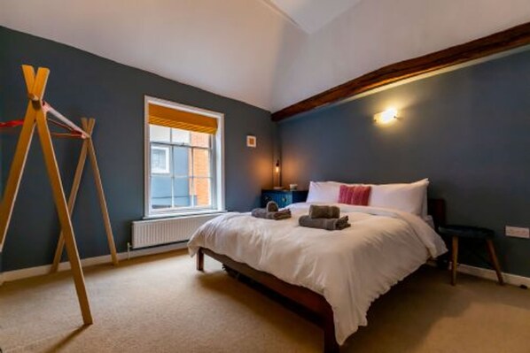 A bedroom with a bed, a window, a radiator, and a wooden ladder. - Host Stay Princes Cottage (Norwich)