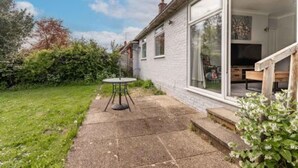Une maison avec un patio, une table ronde et un téléviseur dans le salon.