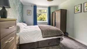 Une chambre à coucher comprenant un lit, une commode, une fenêtre avec des rideaux et une armoire.