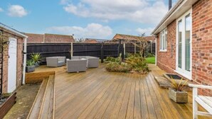 A wooden deck with outdoor furniture, a brick house, and a fenced backyard. - Host Stay Gorse Cottage (Norwich)