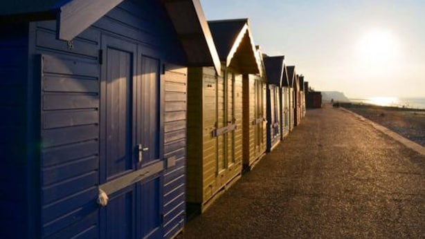A row of beach huts with a gravel path leading to the beach. - Host Stay West Street Cottage (Cromer)
