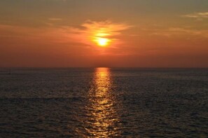 A sunset over a calm sea with a visible horizon line. - Host Stay West Street Cottage (Cromer)