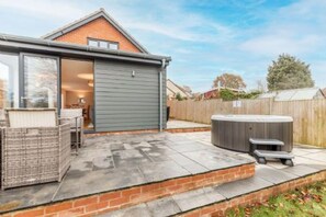 A modern house with a patio area, a hot tub, and a covered outdoor seating area. - Host Stay Crimond House (Cromer)