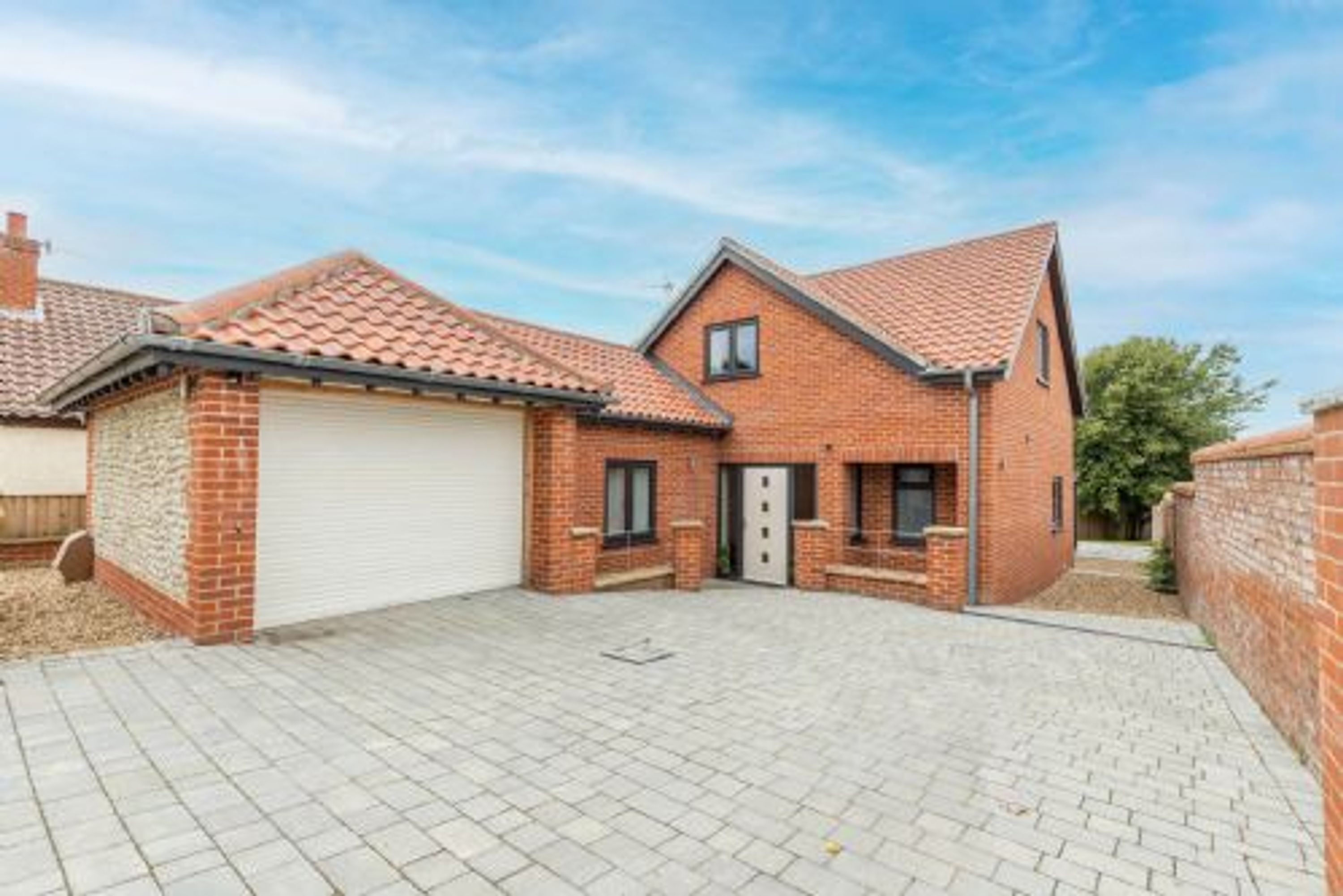 Et toetagers hus med tegltag, garage og en asfalteret indkørsel.