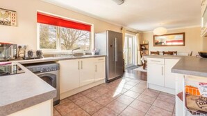 Una cocina moderna con lavadora integrada, refrigerador y comedor con vistas al exterior.