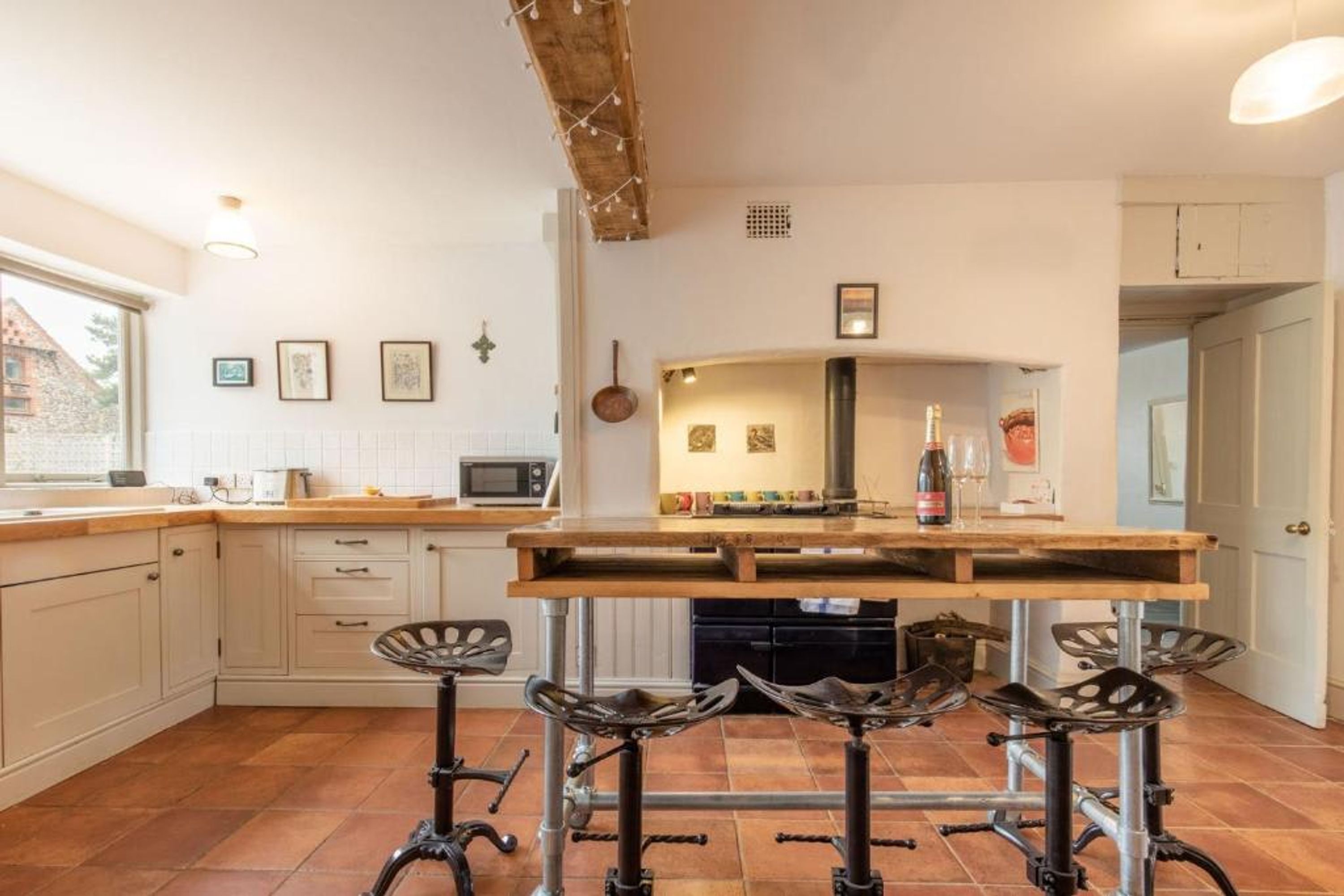A kitchen with a central island, bar stools, a microwave, and a wine bottle.