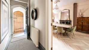 A hallway with a wooden door, a radiator, and a dining area with a table and chairs. - Host Stay Bressingham Lodge (Diss)