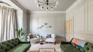 A living room with two green sofas, a white armchair, a coffee table, and a decorative wall piece. - Host Stay Bressingham Lodge (Diss)