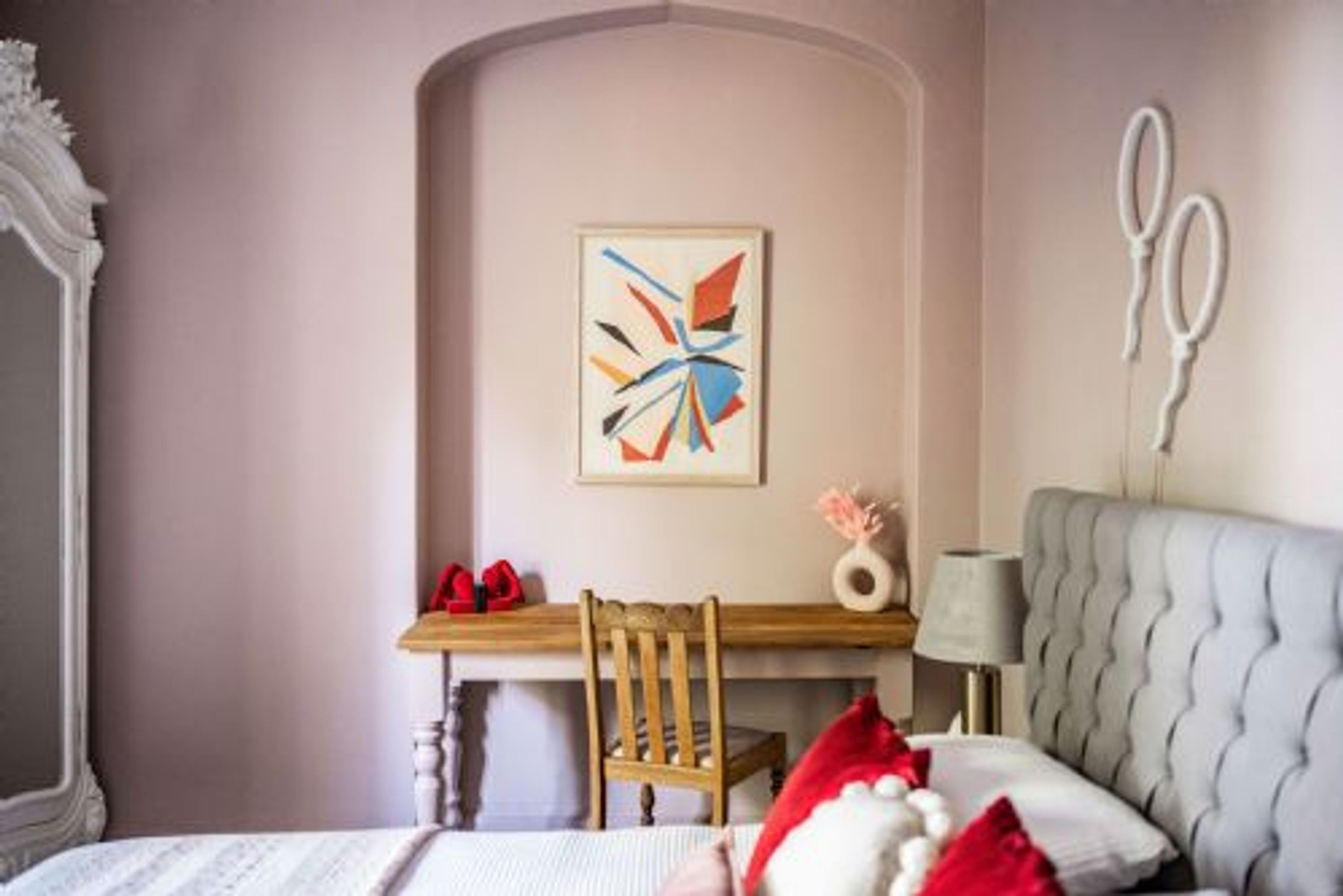 Un dormitorio con cama, escritorio, silla, lámpara y un adorno en la pared.