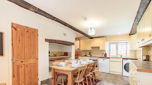 A kitchen with a wooden dining table, chairs, and a tiled floor. - Host Stay 2 Ruscon Cottage (King's Lynn)