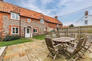 A brick house with a tiled roof, a front door, and a small front yard with a wooden fence. - Host Stay 2 Ruscon Cottage (King's Lynn)
