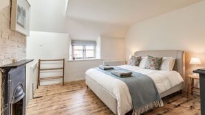 Un dormitorio con cama, radiador, ventana y chimenea.