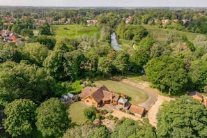 An aerial view of a rural property with a large house surrounded by lush greenery and a river.