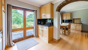 A spacious kitchen with wooden cabinets, a dining area, and a large window offering a view of greenery.