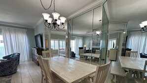 A spacious living room with a large wooden dining table, comfortable seating, and a television.
