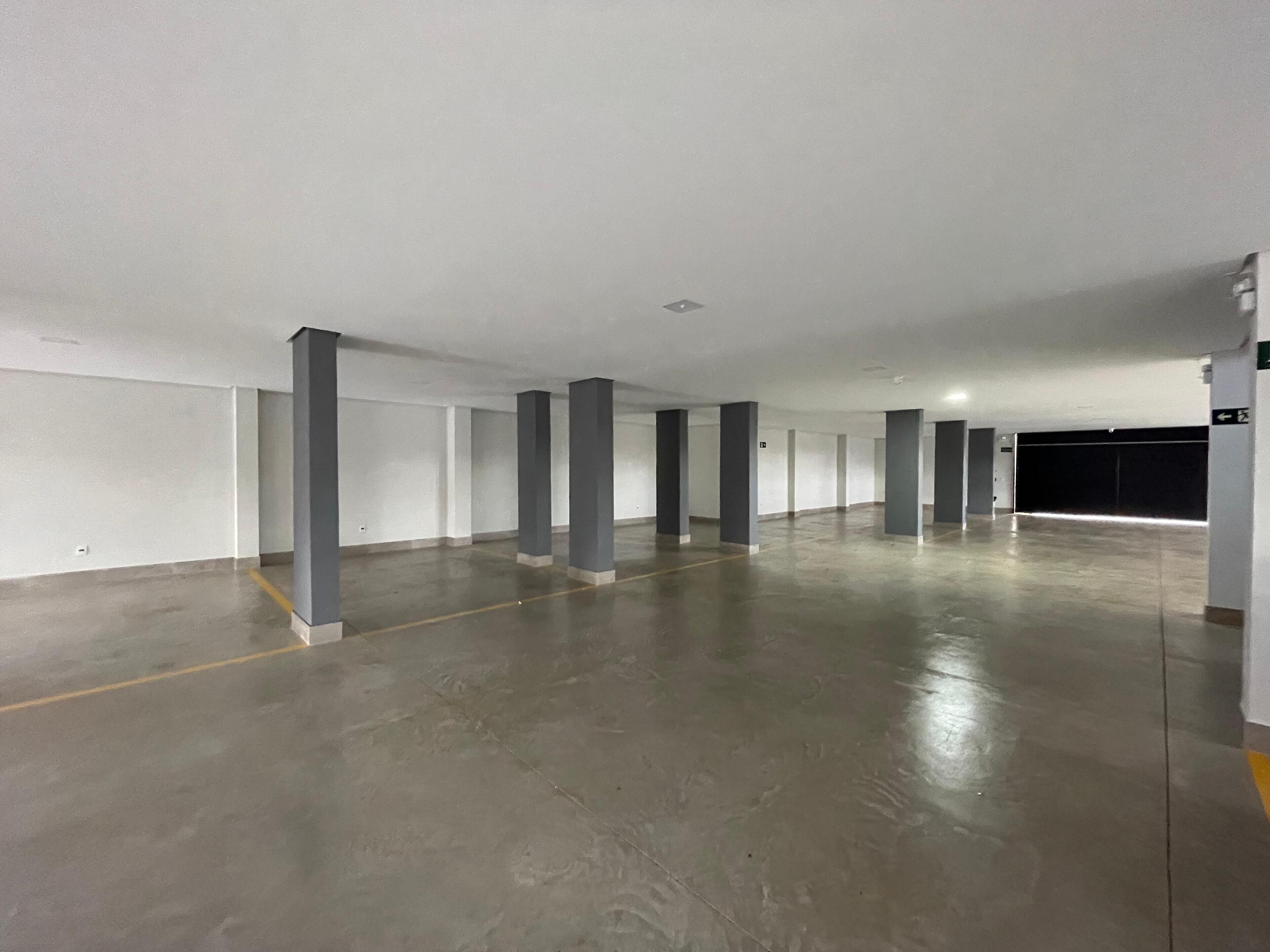 A large, empty parking garage with concrete floors and white walls.
