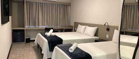 Habitación de hotel con dos camas, un armario, un espejo y un equipo de aire acondicionado.