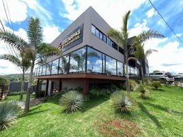 Um hotel moderno com fachada de vidro, palmeiras e céu claro.