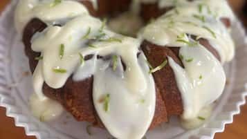 A bundt cake with white icing and green garnish on a white plate.