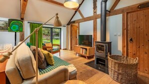A cozy living room with a sofa, a television, a fireplace, and a wooden ceiling. - Host Stay The Old Church Hall (Holt)