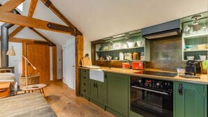 A kitchen with green cabinets, a built-in oven, and a wooden ceiling. - Host Stay The Old Church Hall (Holt)