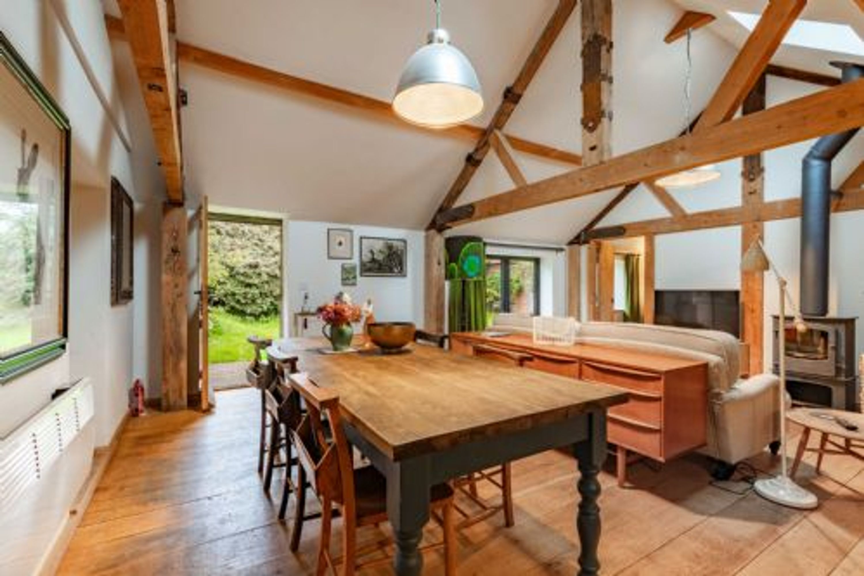 A rustic interior with exposed wooden beams, a wooden dining table, and a cozy seating area.