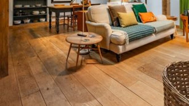 A spacious loft with exposed wooden beams, a cozy seating area with a sofa and chairs, and a dining table. - Host Stay The Old Church Hall (Holt)