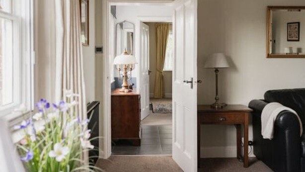 A hallway with a wooden desk, a lamp, and a black leather chair. - Host Stay Manor View (Fakenham)