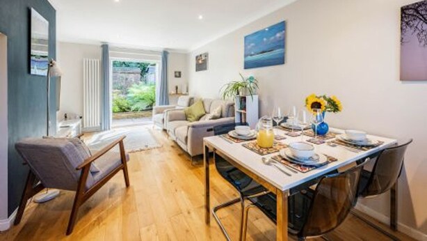 A dining area with a table set for four, a sofa, and a view of the outdoors. - Host Stay Maple House (Norwich)