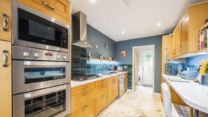 A modern kitchen with stainless steel appliances, wooden cabinets, and a marble countertop. - Host Stay Maple House (Norwich)
