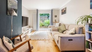 A modern living room with a sofa, armchair, and a bookshelf. - Host Stay Maple House (Norwich)