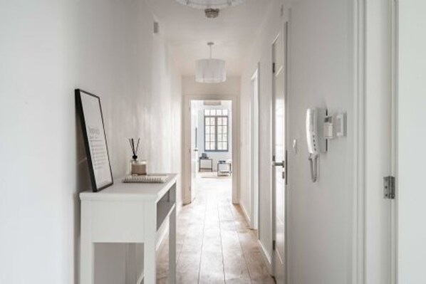 A hallway with a white console table, a framed picture, and a telephone.