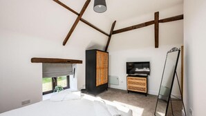 Une chambre à coucher comprenant un lit, une télévision, une armoire et un miroir.