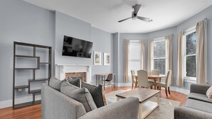 Una sala de estar moderna con chimenea, un televisor de pantalla plana y un comedor con mesa y sillas.