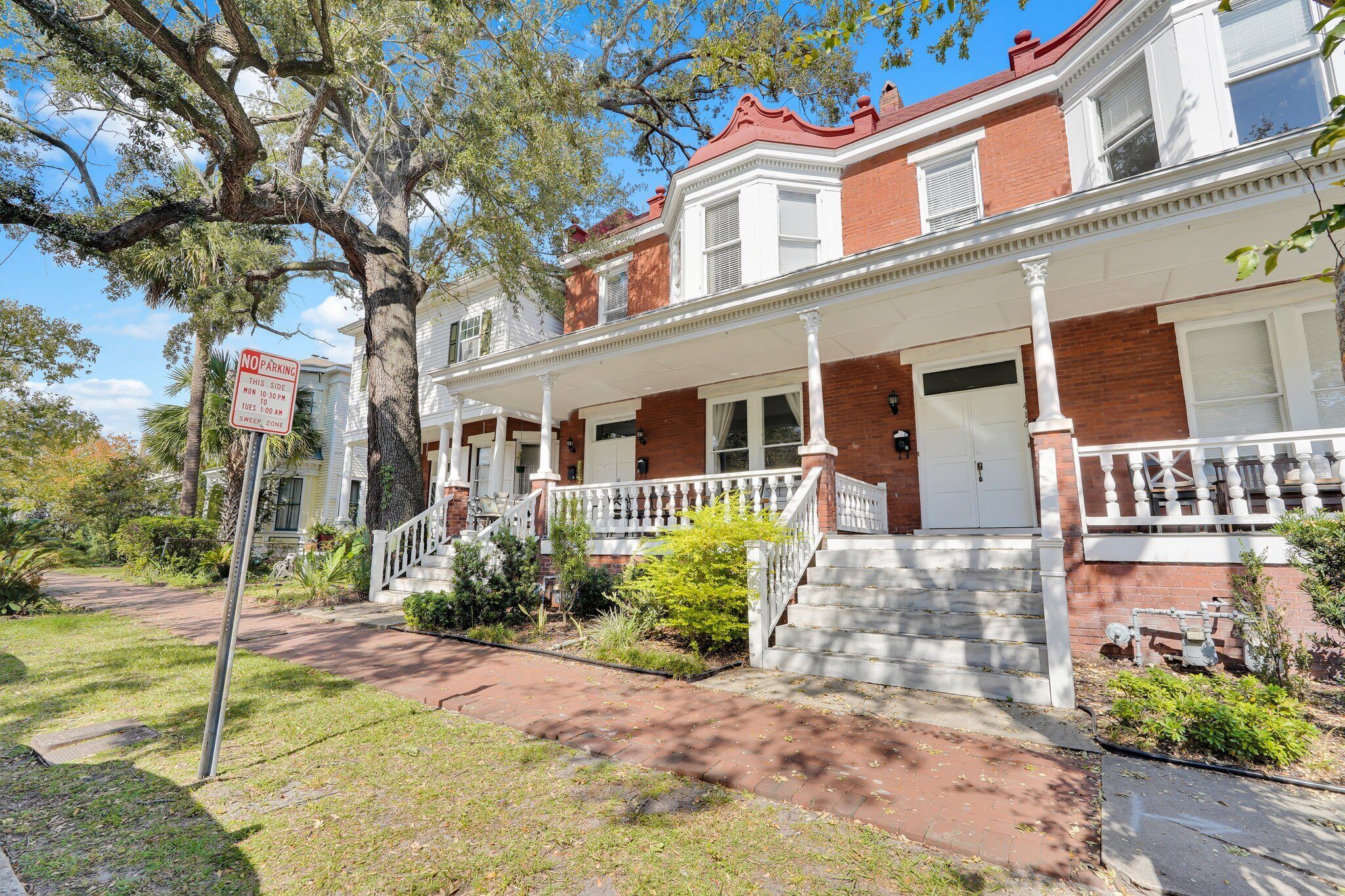 A two-story brick house with a front porch, a "No Parking" sign, and a well-maintained lawn.