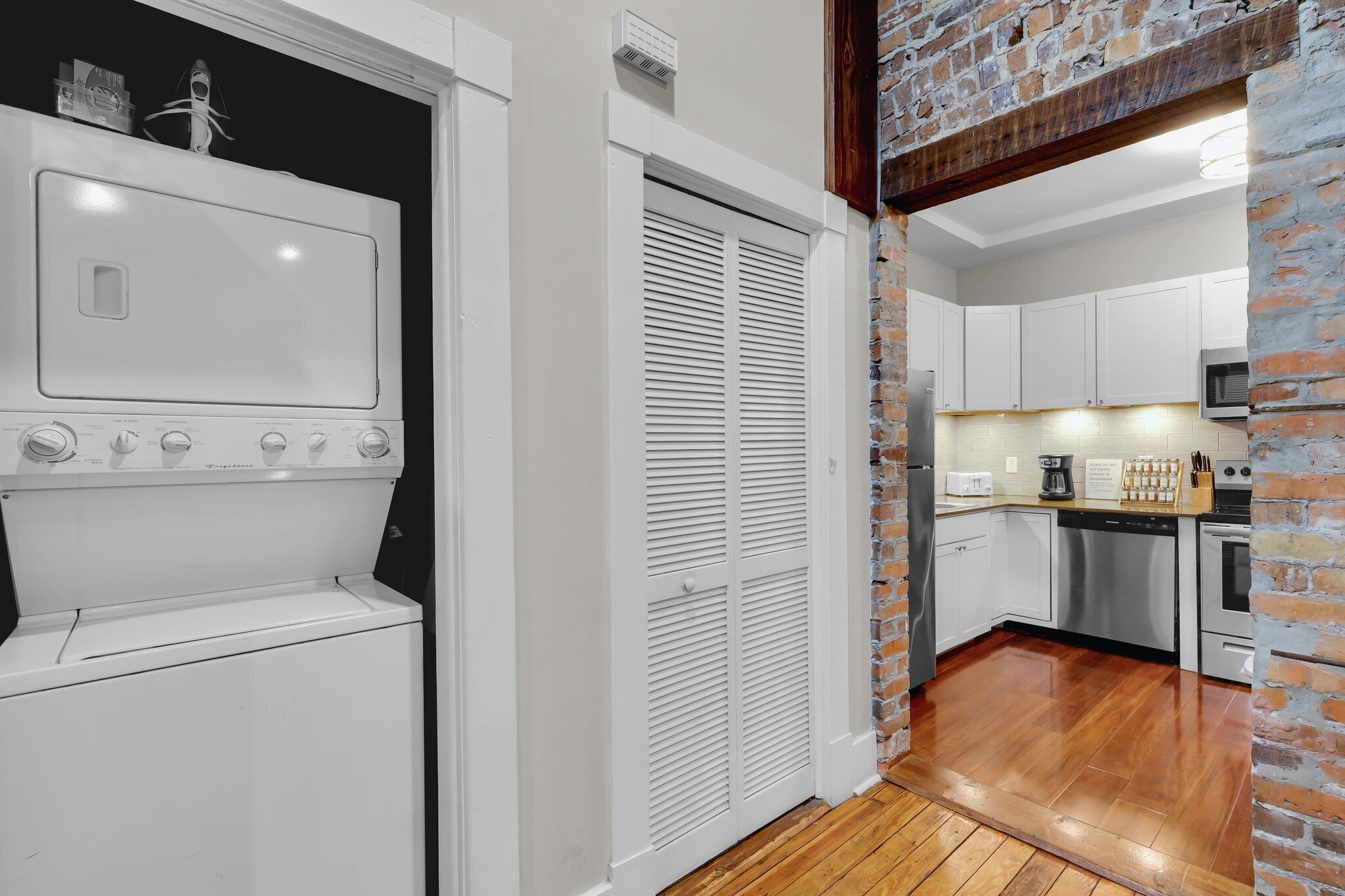 A compact kitchen with white cabinets, a stainless steel dishwasher, and a microwave.